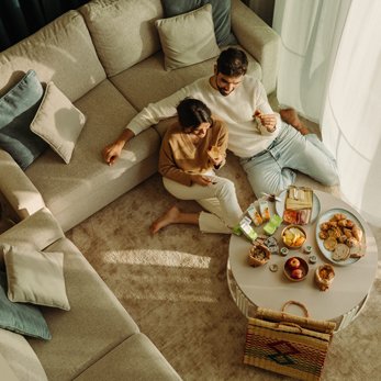Casal jovem a tomar o pequeno-almoço na sala de um apartamento acolhedor nos Apartamentos Dom Pedro Residence, em Vilamoura.