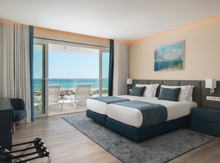 Quarto com cama de casal, varanda e vista para o mar com espreguiçadeiras, banheira no quarto, nos apartamentos de luxo do Dom Pedro Residences em Vilamoura, Algarve.