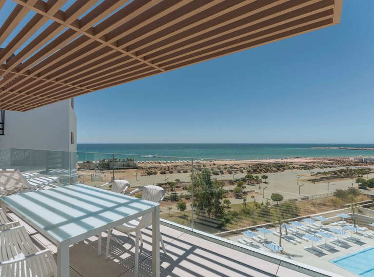 Vista das varandas dos apartamentos de luxo do Dom Pedro Residences em Vilamoura, Algarve, mostrando a zona da piscina e o mar ao fundo.